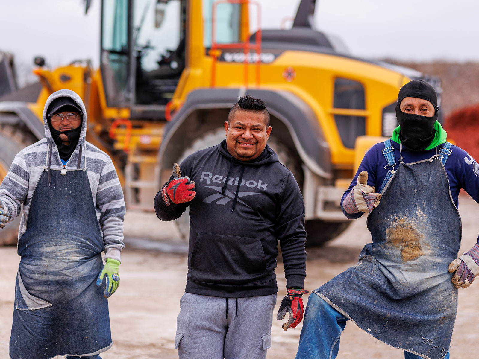 Three Rademann Stone employees posing for the camera in front of an end loader