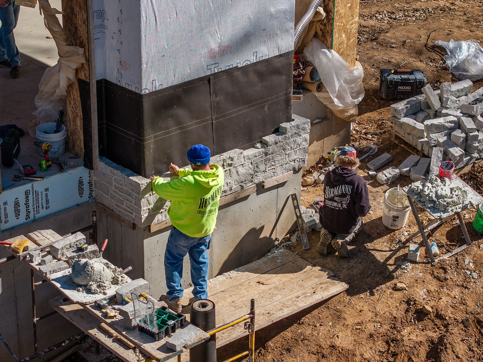 Overhead of two men installing Rademann stone veneer on an exterior fireplace